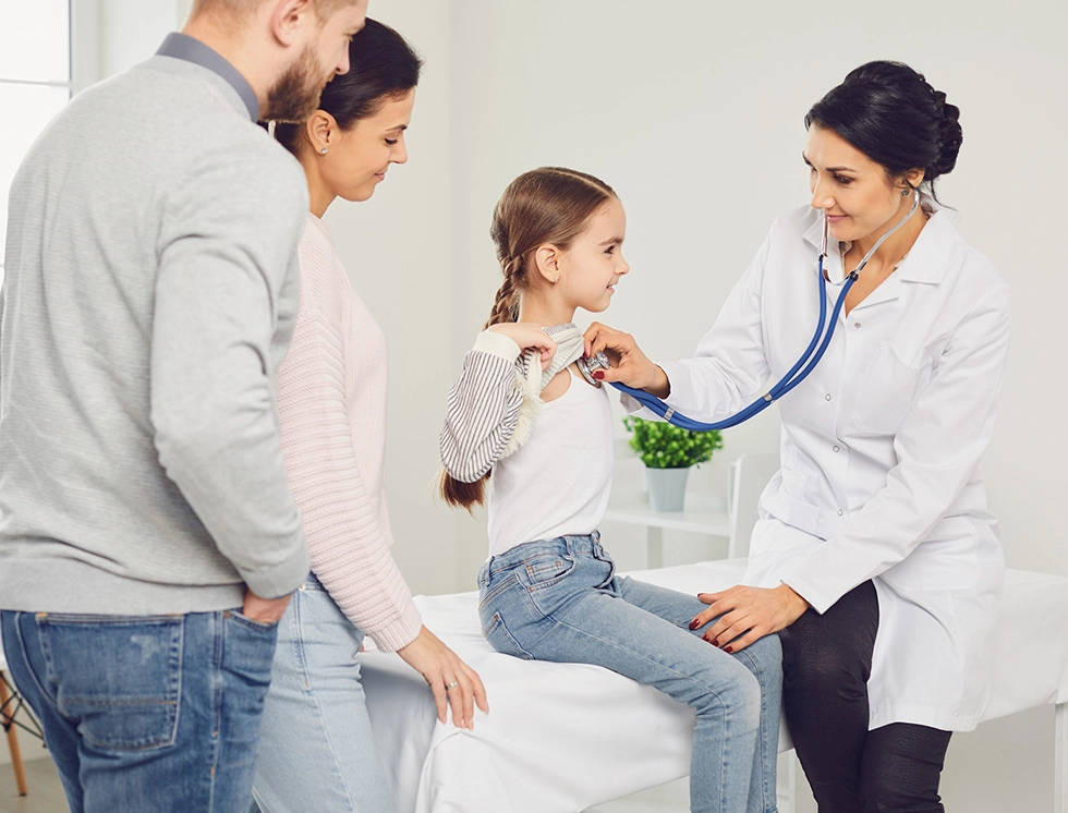 A young girl experiences a routine check-up. Her attentive parents stand by, observing as a friendly doctor examines her with a stethoscope.